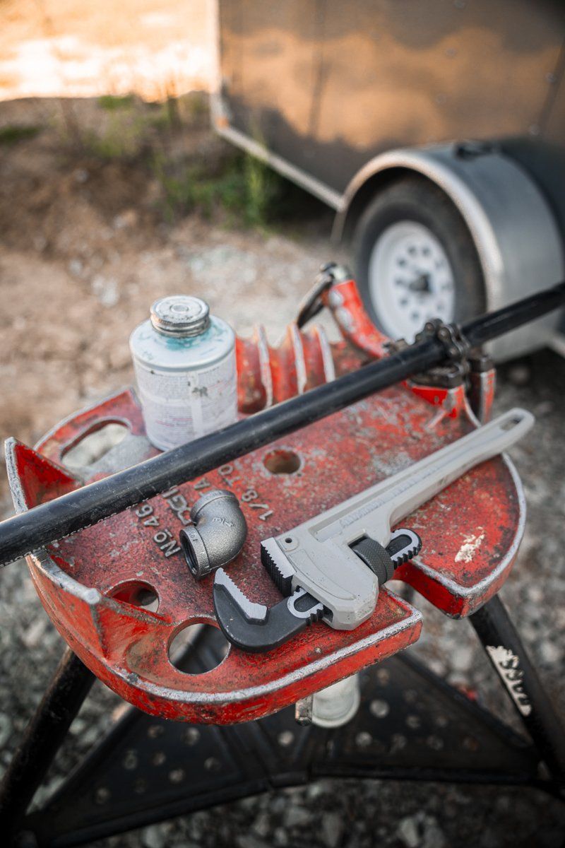 A pipe wrench is sitting on top of a red workbench.