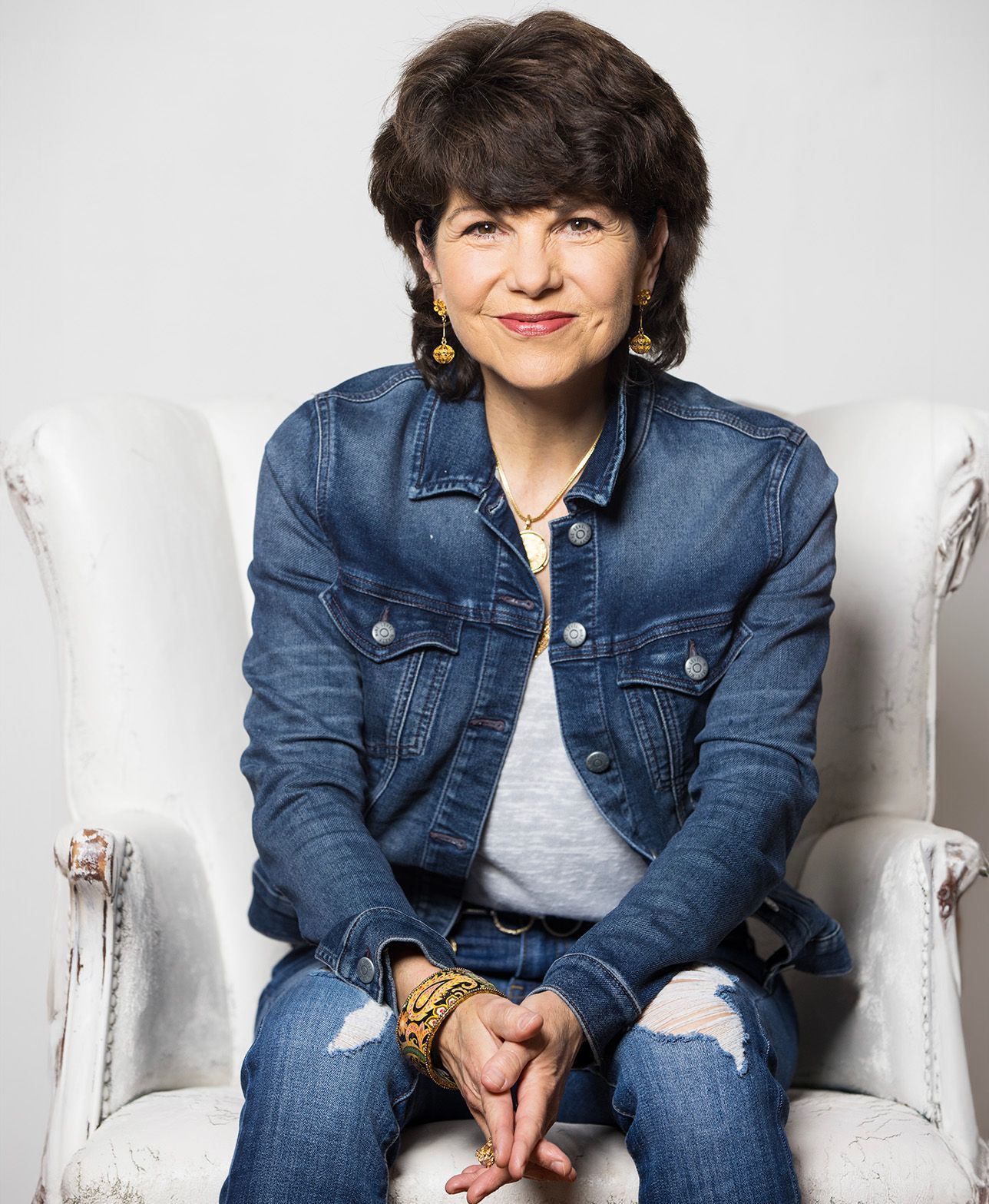 A woman in a denim jacket is sitting in a white chair