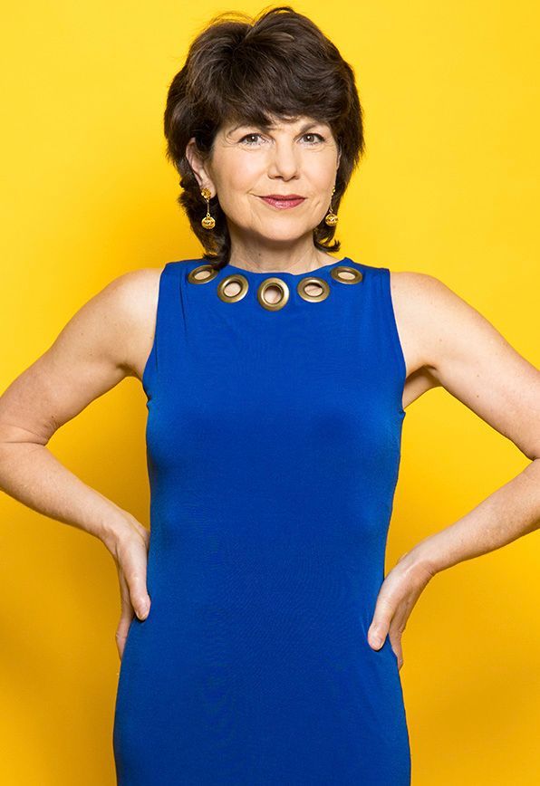 A woman in a blue dress is standing with her hands on her hips