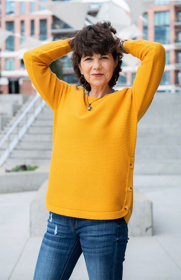 The woman is wearing a yellow sweater and blue jeans.