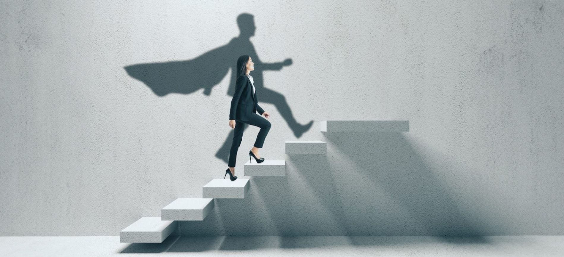 A non-gender person walking up stairs and their shadow is a super human with a cape 