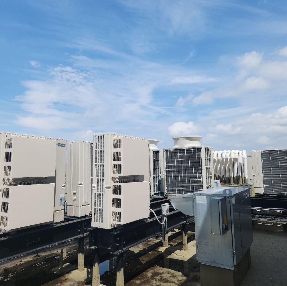 Rooftop with several large, rectangular HVAC units, under a partly cloudy sky.