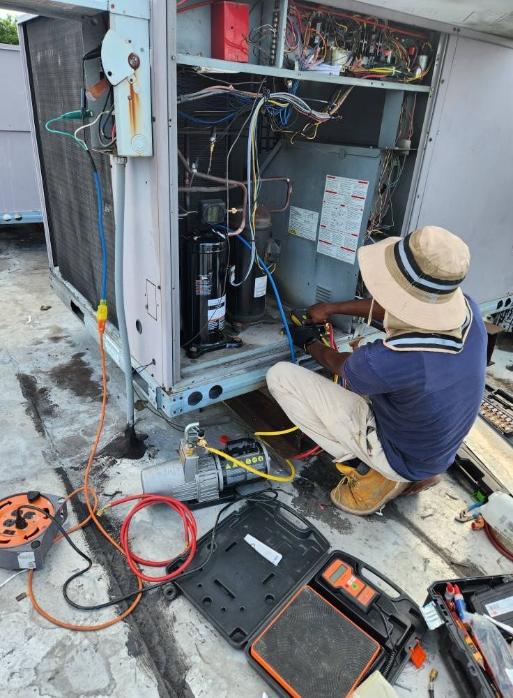HVAC technician repairs an air conditioning unit on a rooftop. He kneels, using tools, with a compressor visible.