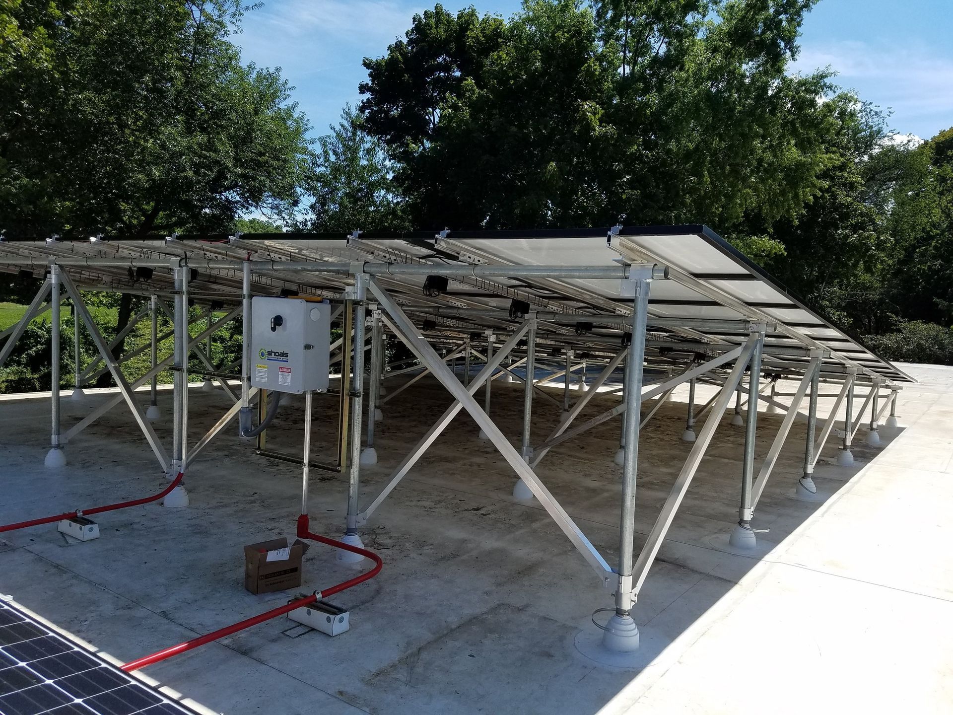 Solar panels mounted on a metal framework on a flat roof, with electrical components visible.