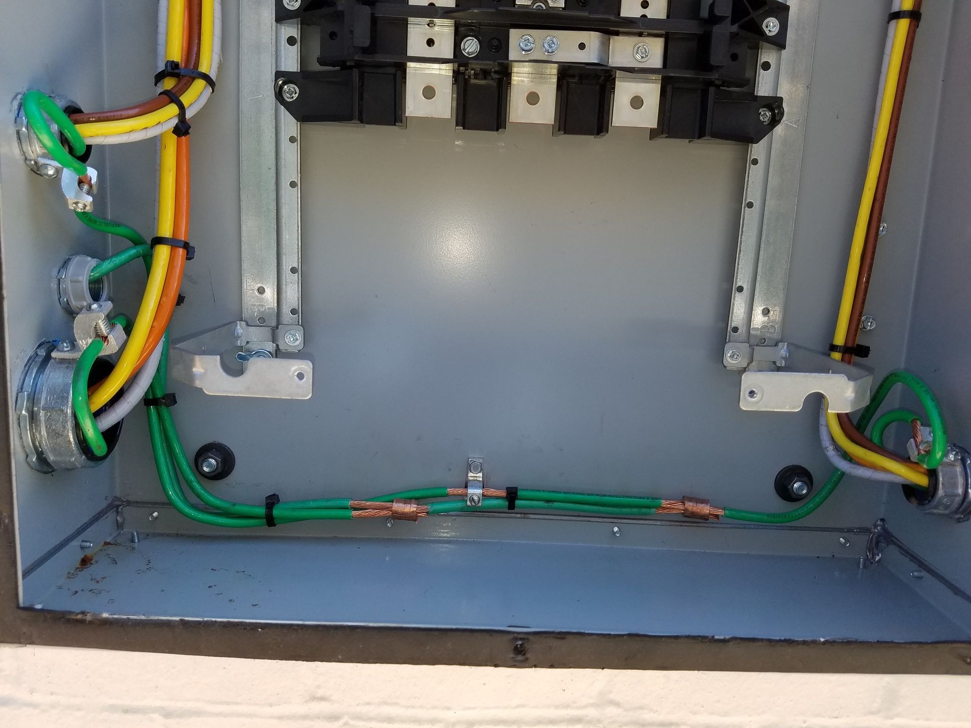 Electrical panel with copper grounding wires connected, conduit, and colored wiring inside.