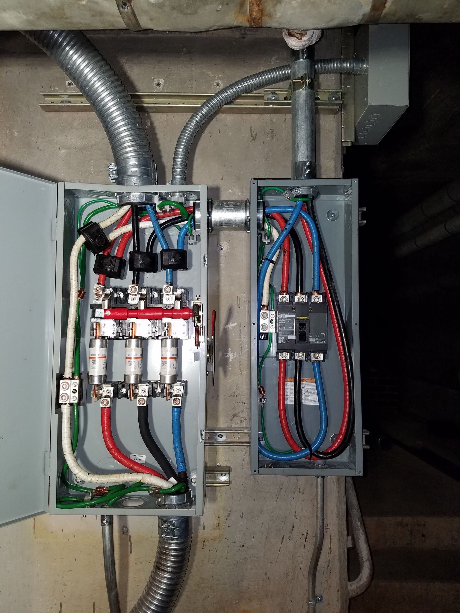 Electrical panels with wires and fuses installed on a concrete wall.