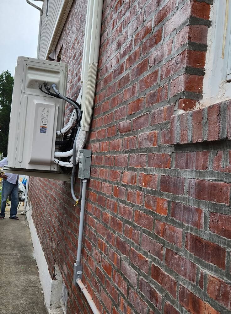 Exterior of a brick building with a mounted air conditioning unit and conduit.