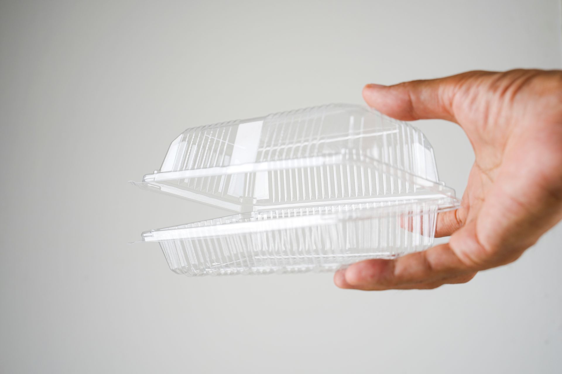 A hand holding a plastic food container.