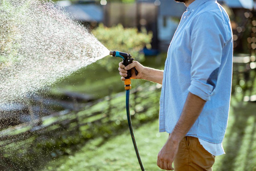 man watering lawn with hand-held sprinkler