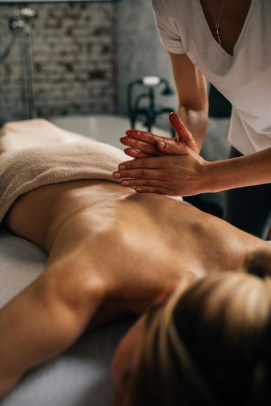 Person receiving a back massage at a spa. Hands massaging back with oil.