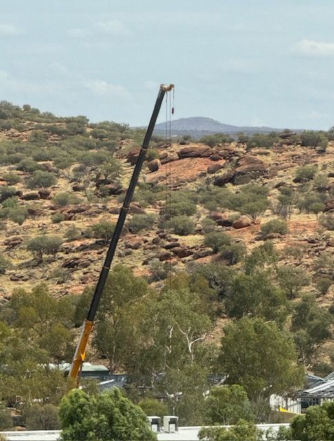 A large crane is sitting on top of a hill in the desert.
