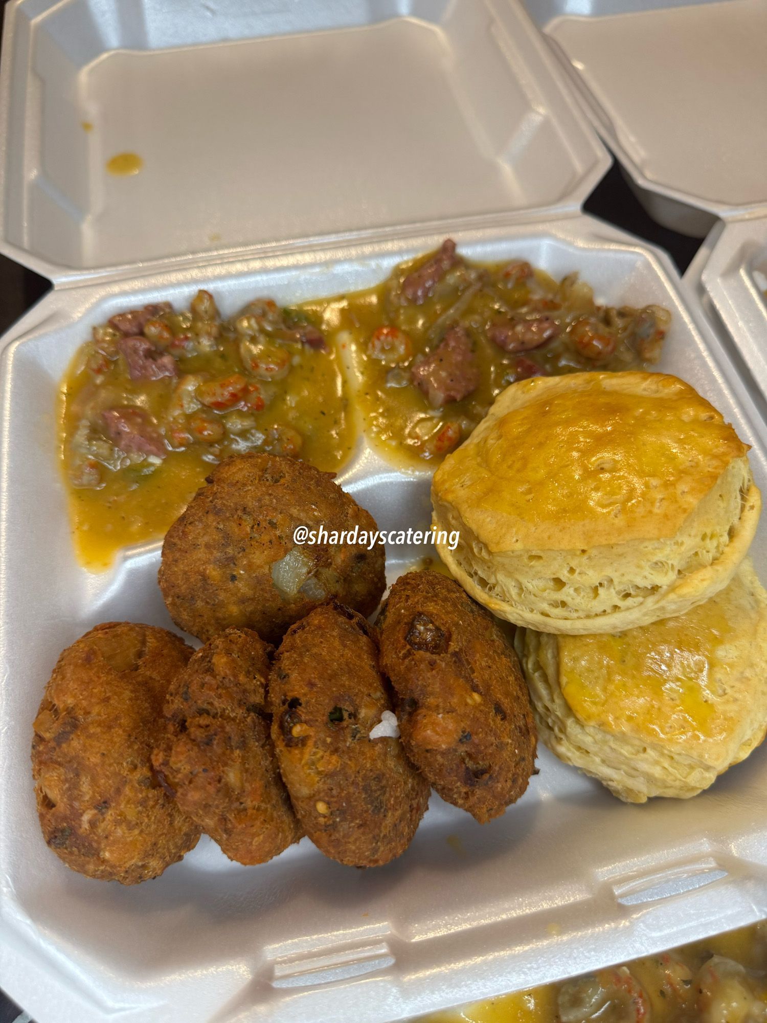 A styrofoam container filled with fried food and biscuits.