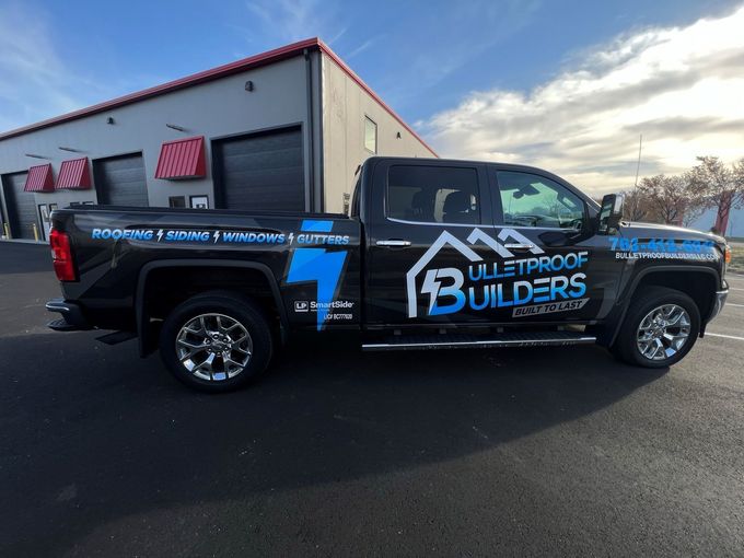 A Bulletproof Builders truck is parked in front of a building.