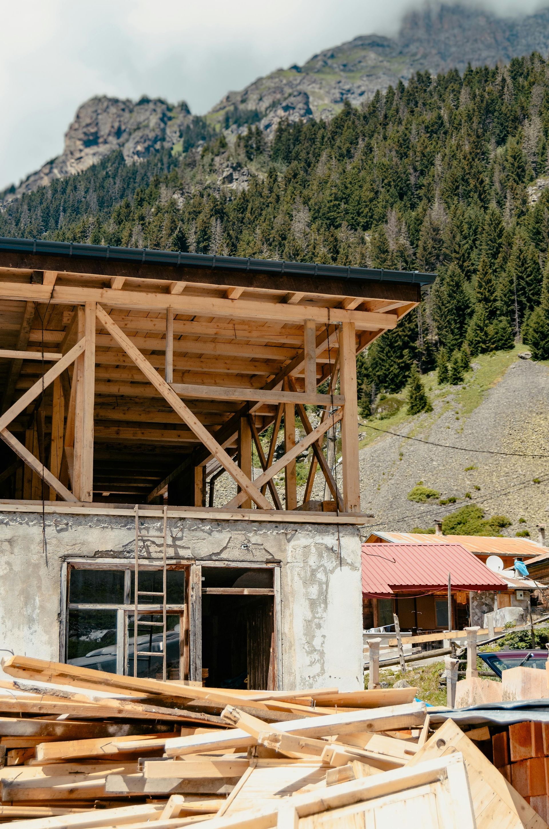 A building is being built in the mountains with a mountain in the background.