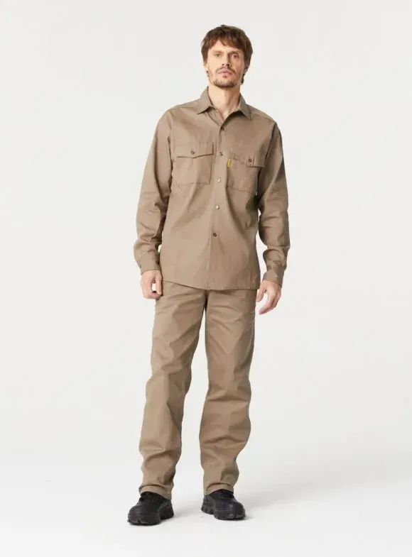 Hombre con camisa abotonada y pantalones de color marrón, de pie frente a un fondo blanco.