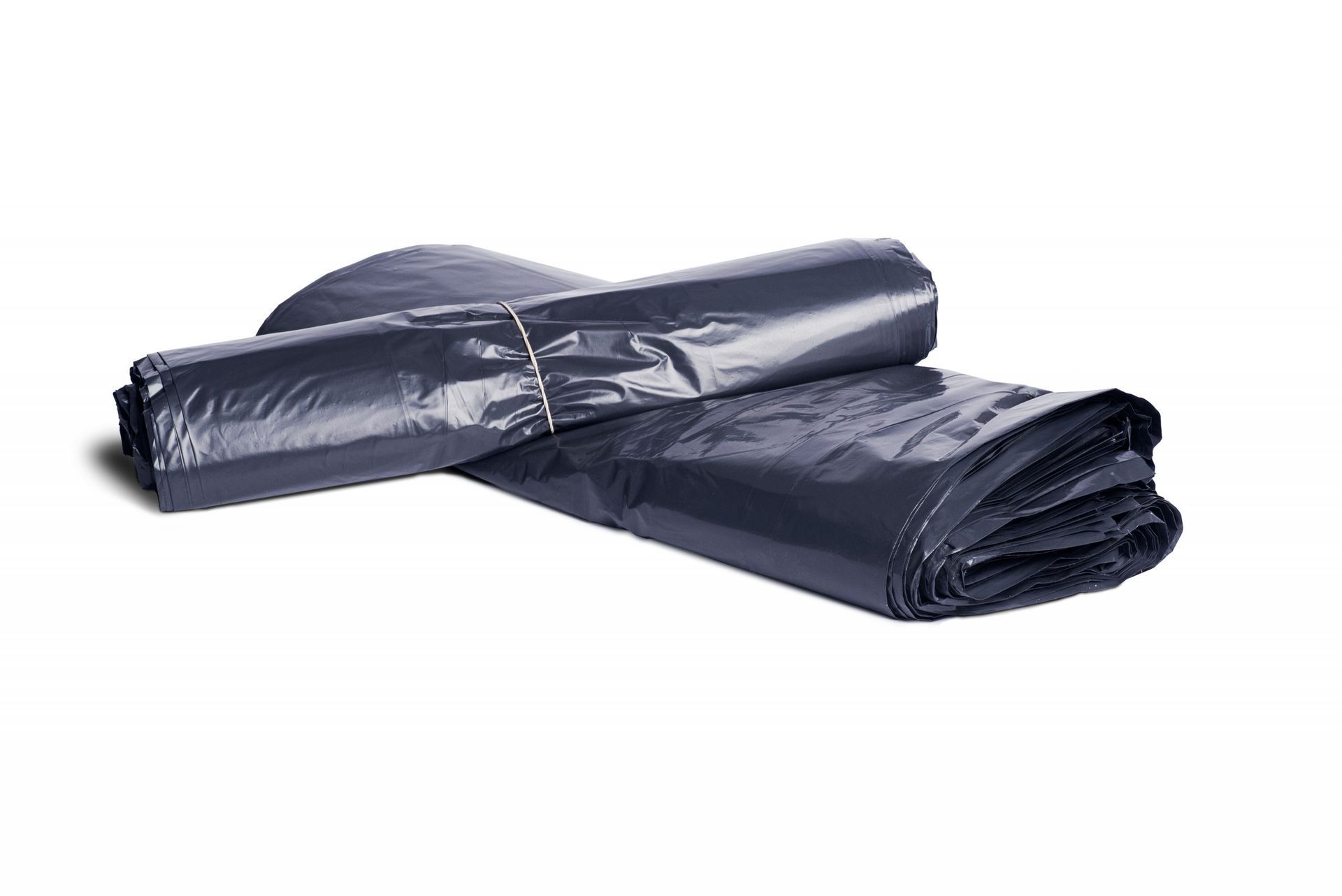 Bolsas de basura de plástico de color gris oscuro, enrolladas y apiladas sobre un fondo blanco.