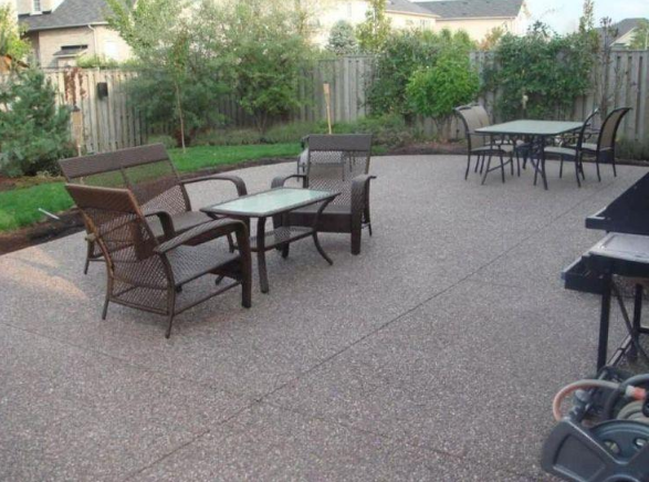 “Spacious concrete patio with outdoor chairs and tables in a fenced backyard during concrete services in Pine Hills, FL”