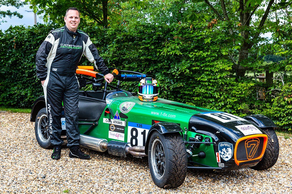 A man is standing next to a green race car with the number 81 on it.