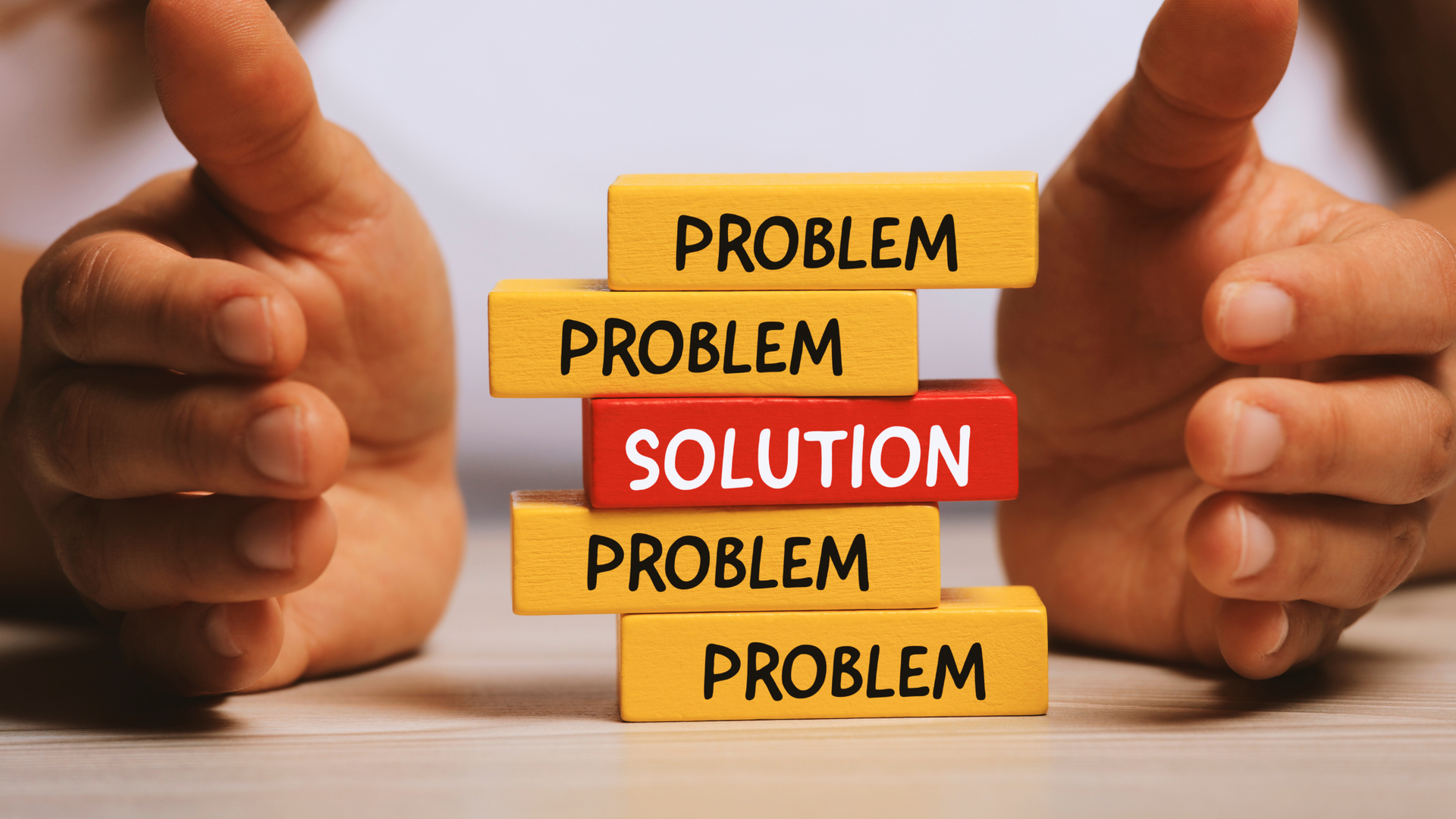 Photo of building blocks saying Problem and Solution with some hands either side