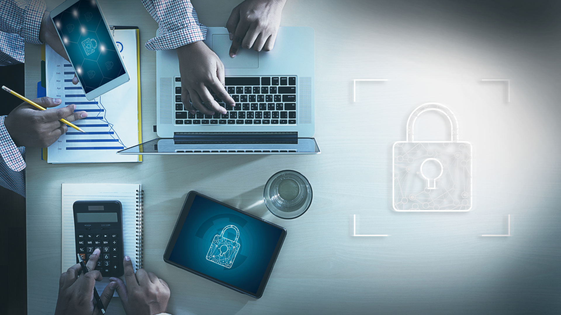 Birds eye view image of people working on laptops with padlocks showing to suggest cyber security.