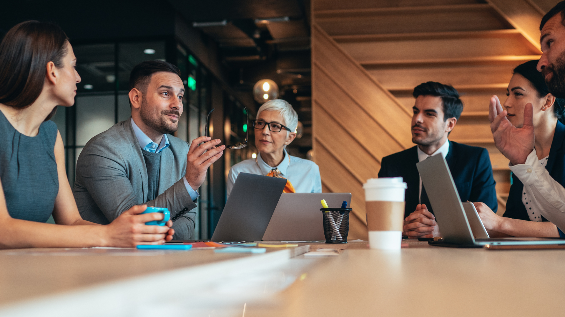 Photo of a group of colleagues sat round a table talking to each other 