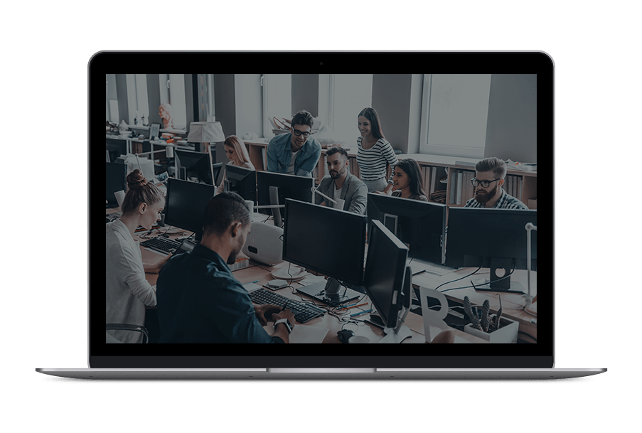 A group of people are sitting at desks in front of computer monitors in an office.