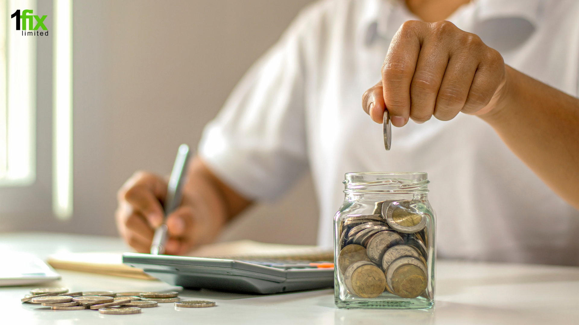 Photo of someone writing notes whilst putting money in a savings jar.