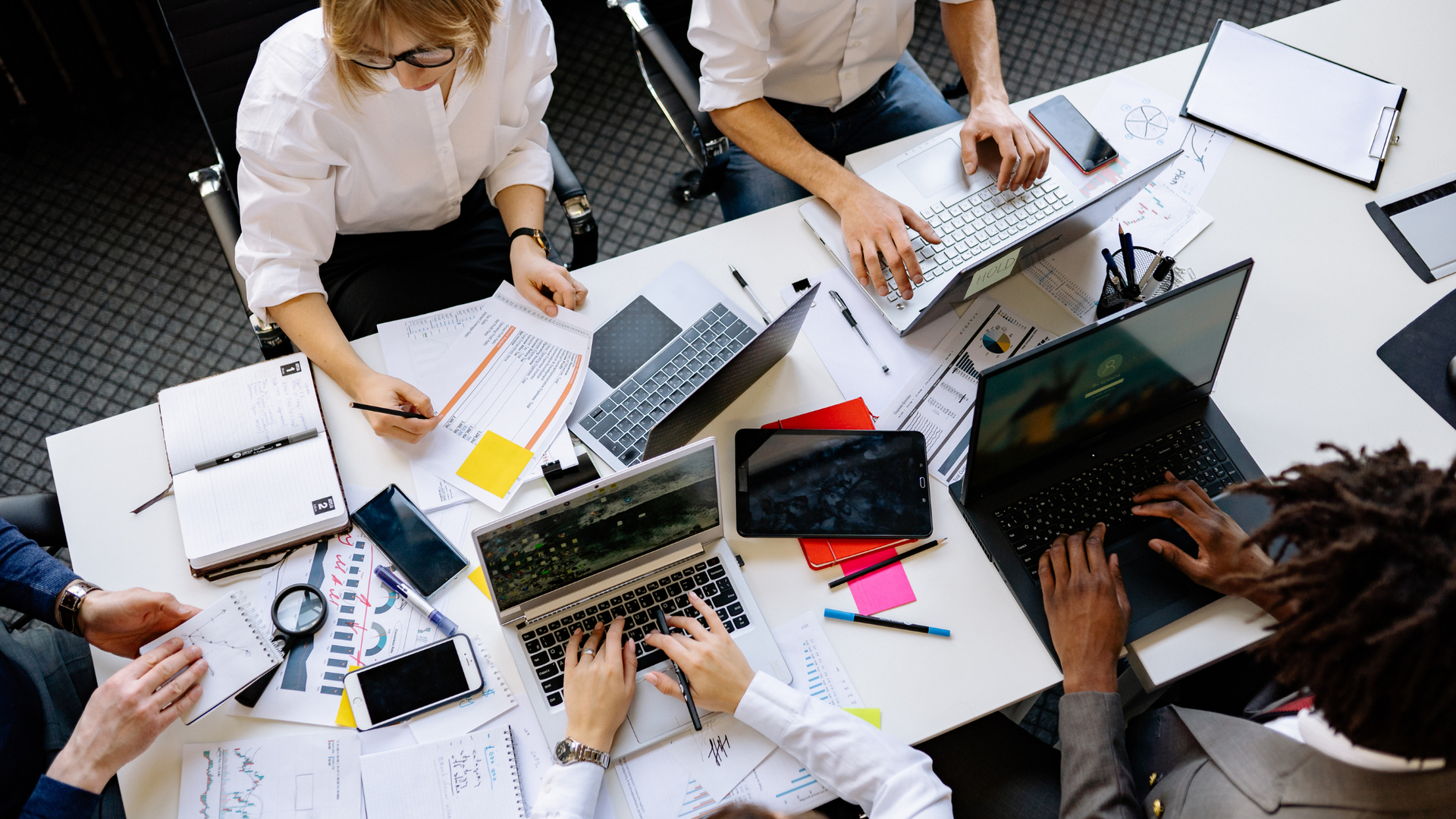 Photo of a birds eye view perspective of people working on multiple devices in an office