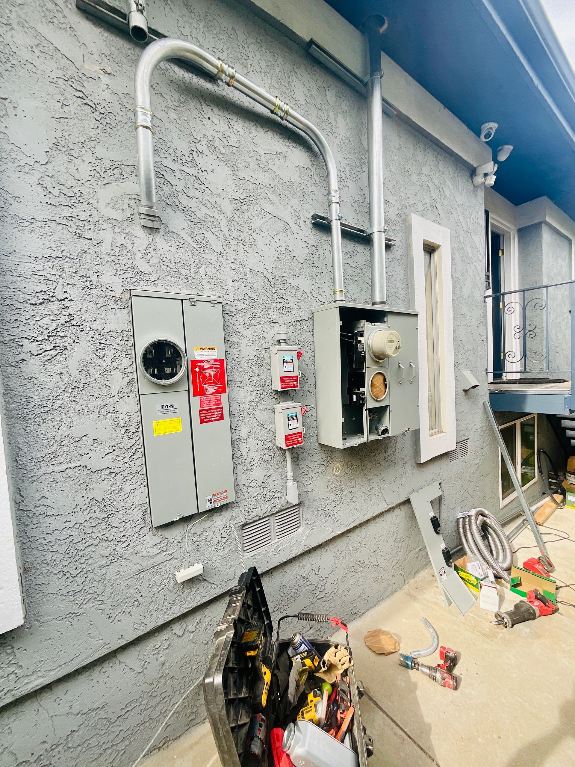 Electrical panel and conduit installed on stucco exterior of a building.