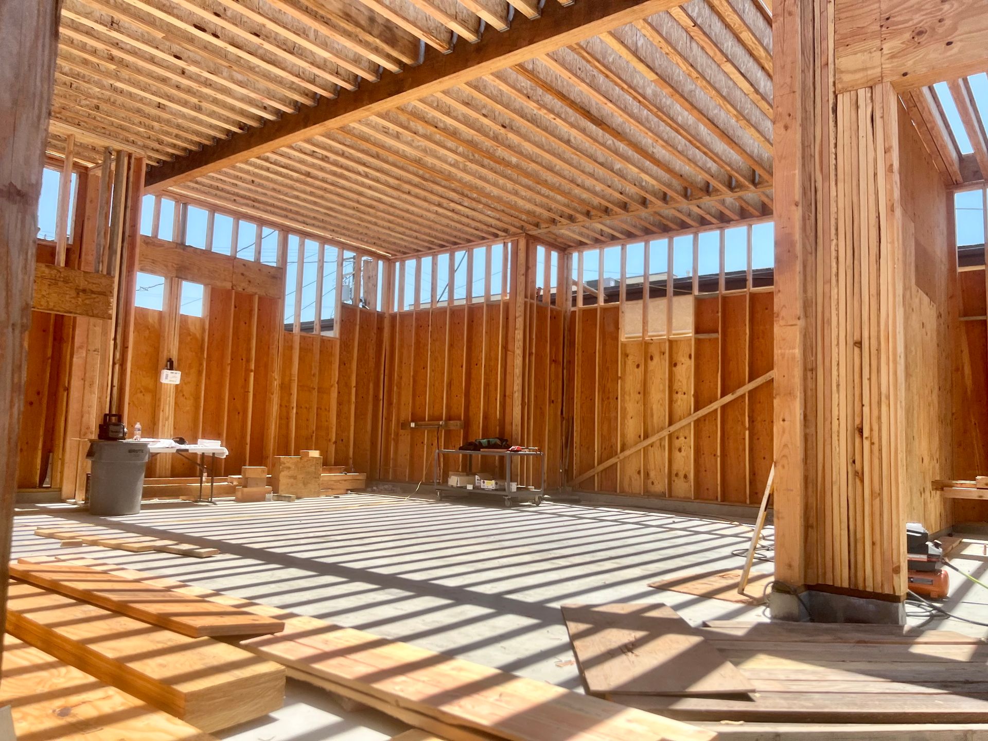 Wooden framework of a building under construction. Sunlight streams through open windows.
