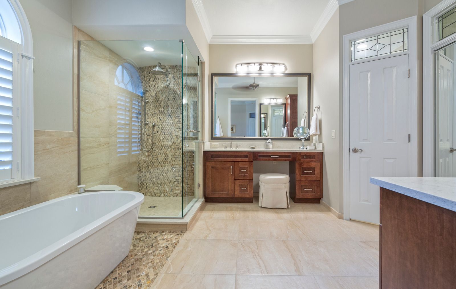 Spacious bathroom with a freestanding tub, glass shower, and wooden vanity with a large mirror.