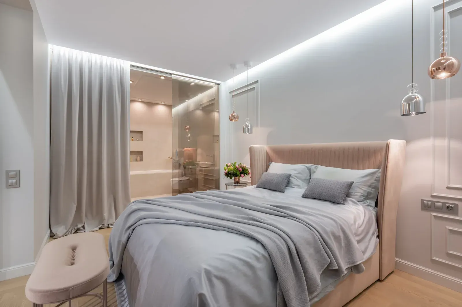 Elegant bedroom with a bed, a wardrobe, and a bench in shades of gray and rose.