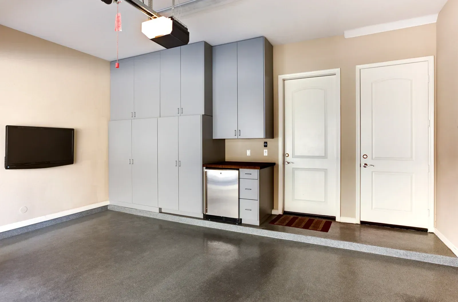 Grey garage with cabinets, doors, TV, and a finished floor.