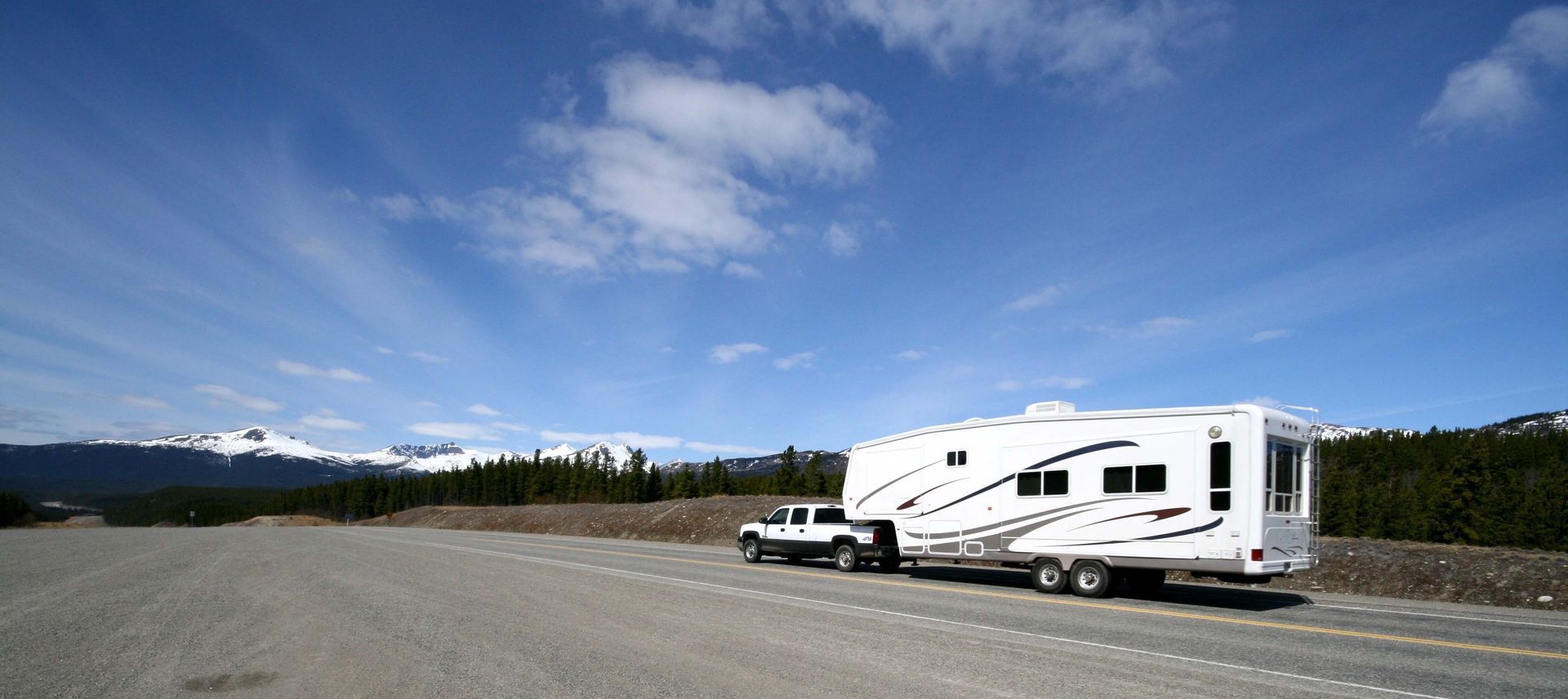 A heavy-duty truck providing RV towing services for a large fifth-wheel trailer on the highway. A heavy-duty truck providing RV towing services for a large fifth-wheel trailer on the highway.