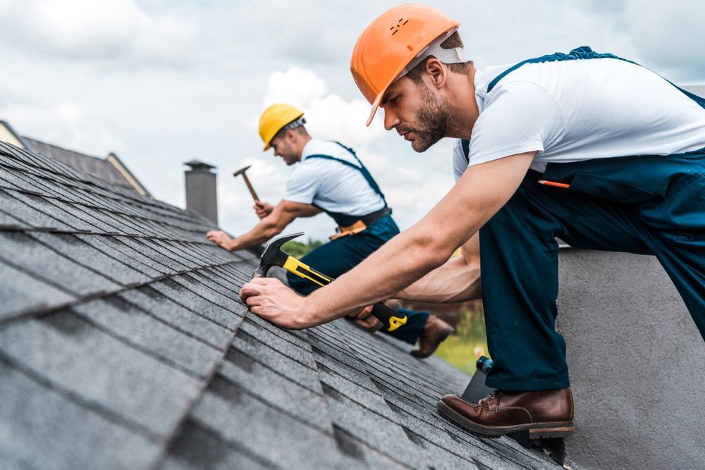 Two men are working on the roof of a house.