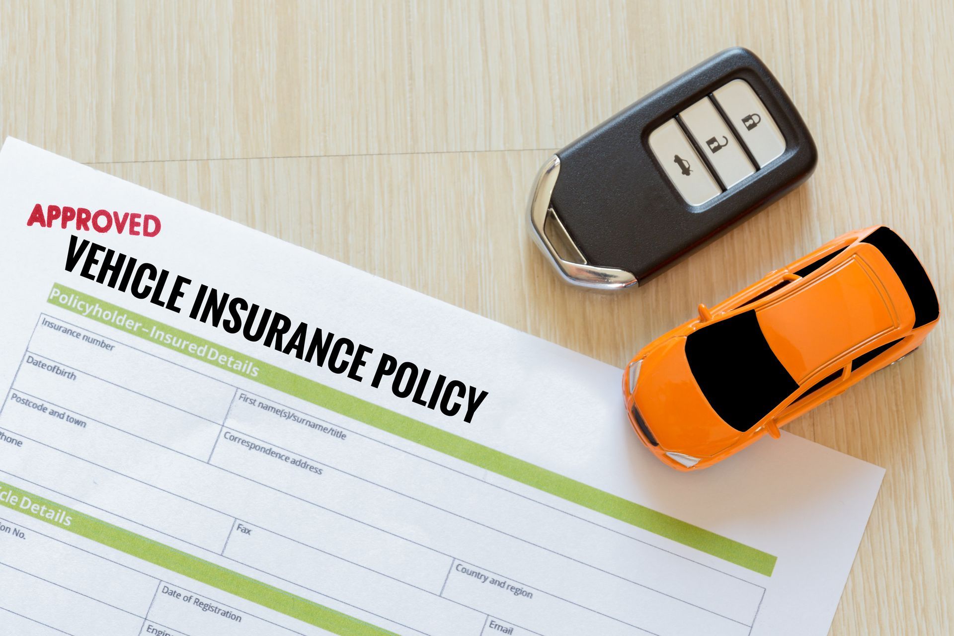 A car insurance claim form with a toy car and a key on the table.