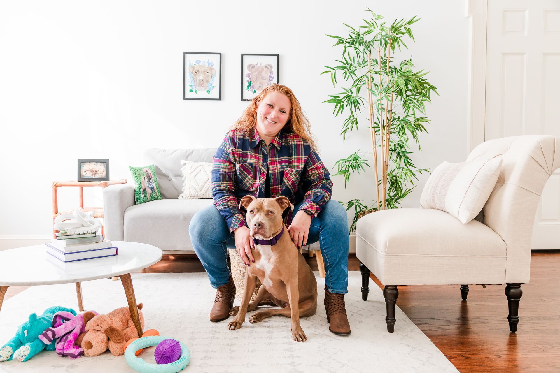 Famale and tan pitbull in living room posing for photo with dog toys