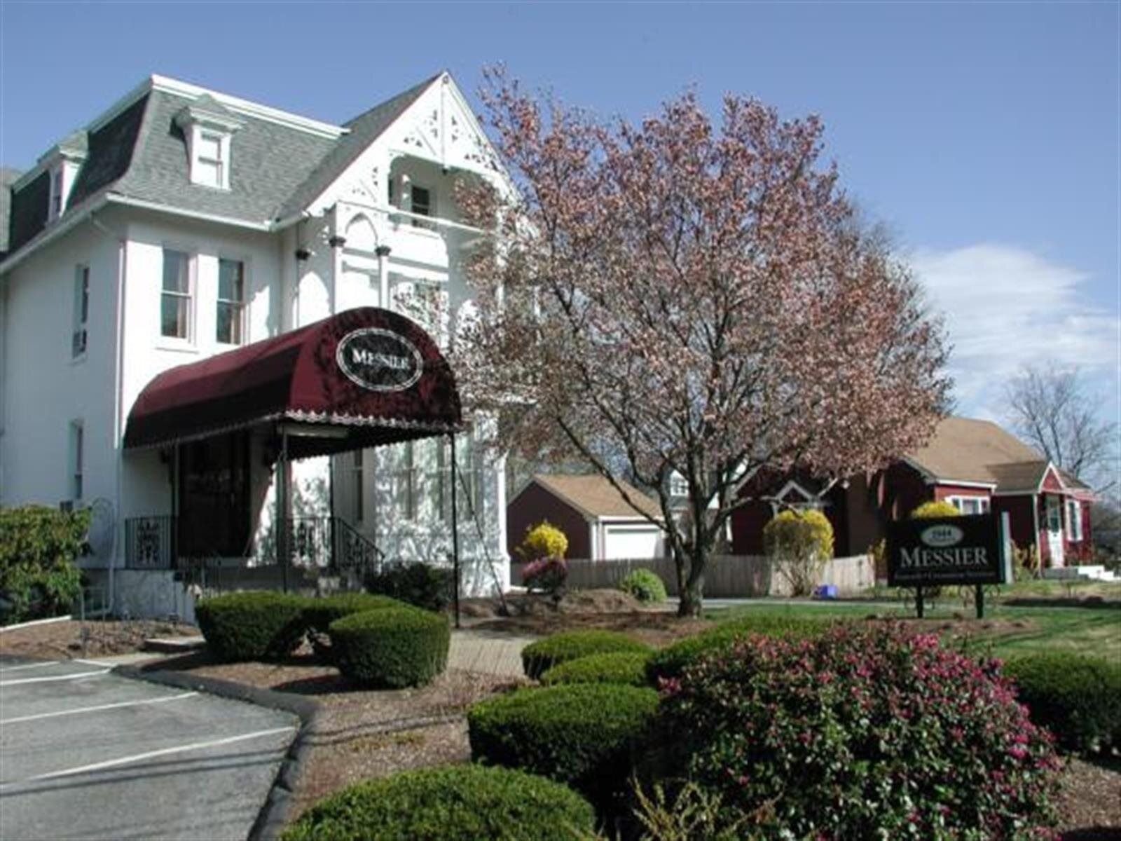 White building with burgundy awning, and a sign that reads 