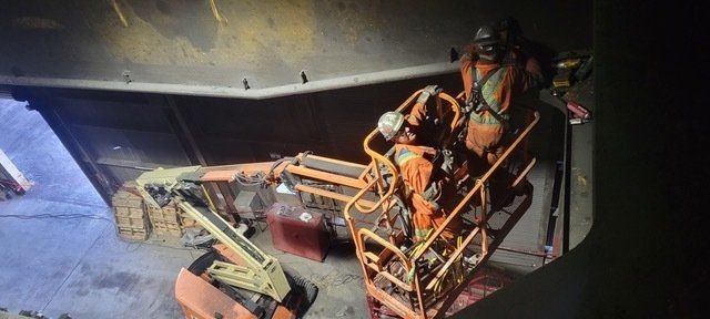 Deux hommes se tiennent debout dans une cage sur une grue.