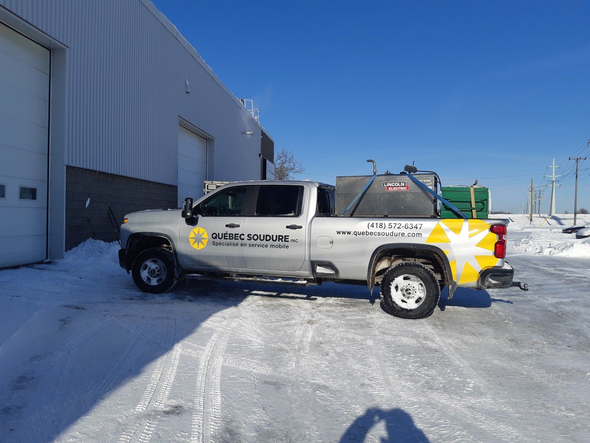 Un camion est garé dans la neige devant un bâtiment.
