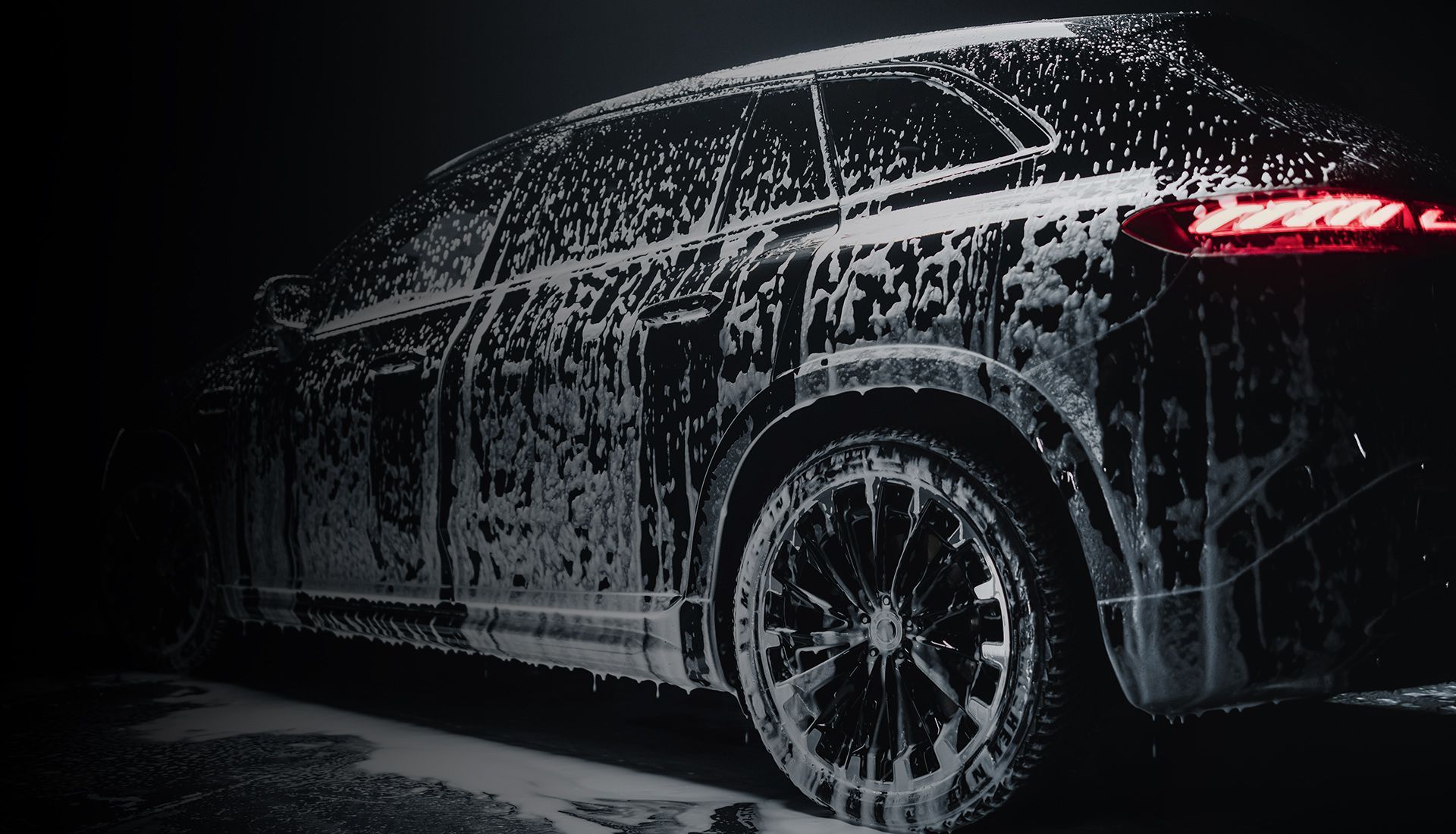 A black car is covered in foam and soap.