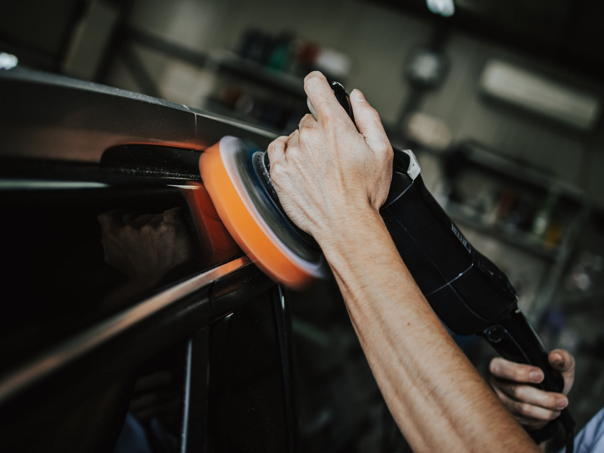 A person is polishing a car with a polisher.