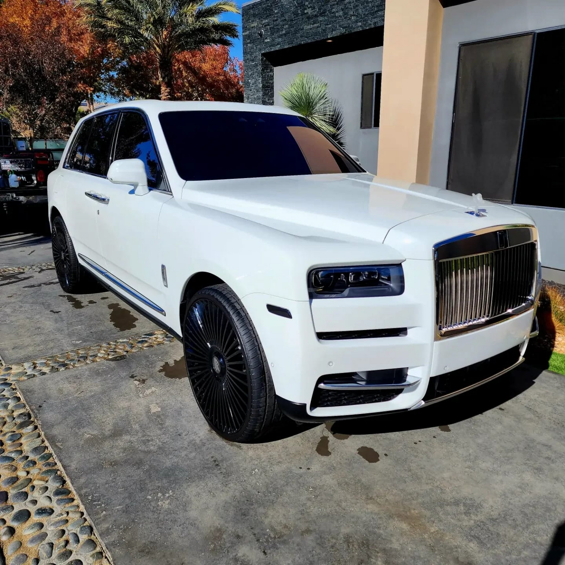 A white rolls royce is parked in front of a house