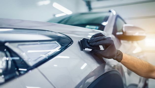 A person is polishing a car with a brush in a garage.