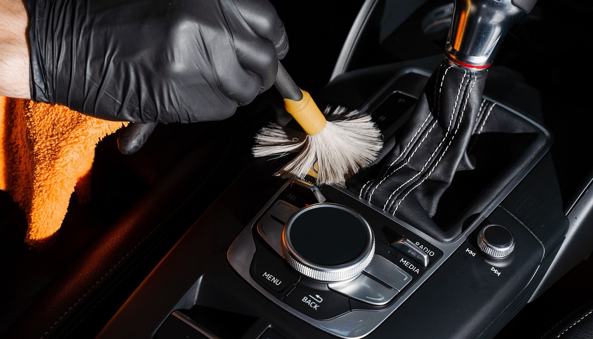 A person is cleaning the interior of a car with a brush.