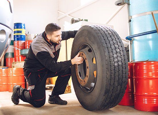 Worker Holding Tire — Peekskill, NY — American Cycle & Tire