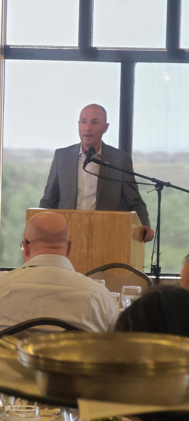A man is standing at a podium giving a speech to a group of people.