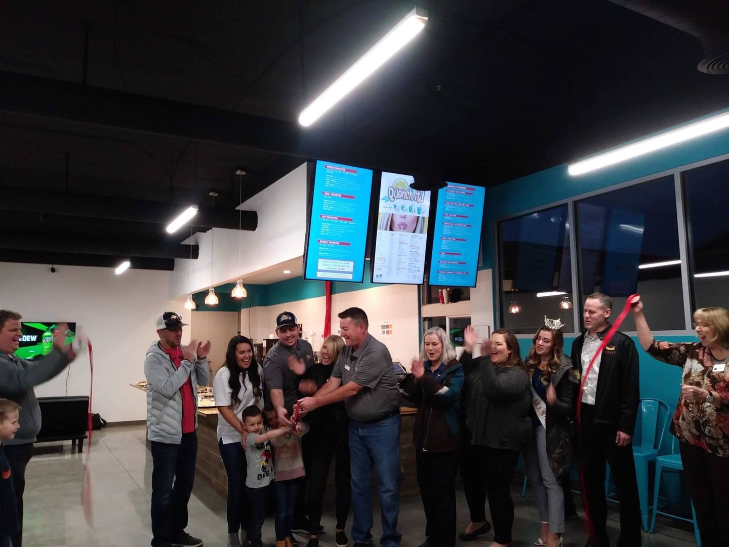 A group of people are standing in a room with a menu on the wall.