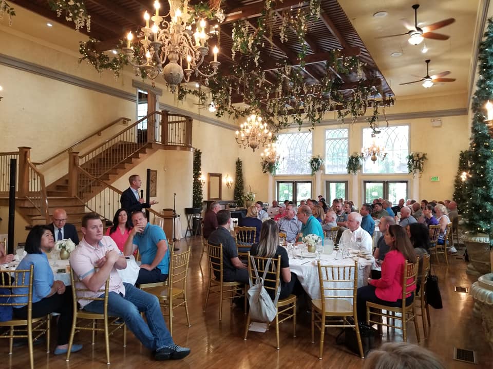 A large group of people are sitting at tables in a large room.