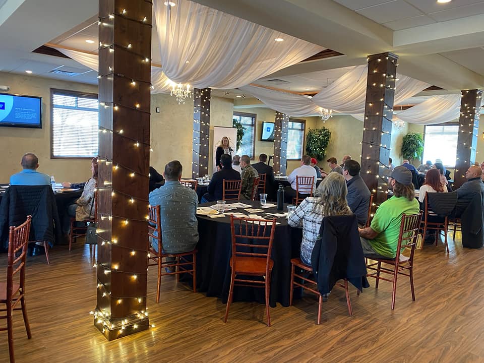 A group of people are sitting at tables in a large room.